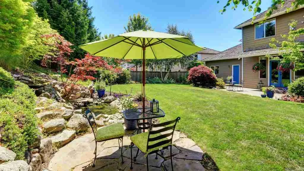 Backyard remodeling featuring a patio seating area, umbrella, and landscaped garden
