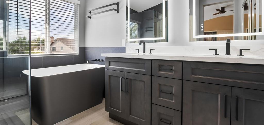 Modern bathroom remodel with black vanity cabinets, freestanding tub, and custom LED mirrors